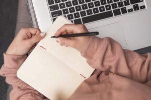 high-angle-female-teacher-home-writing-agenda-during-online-class